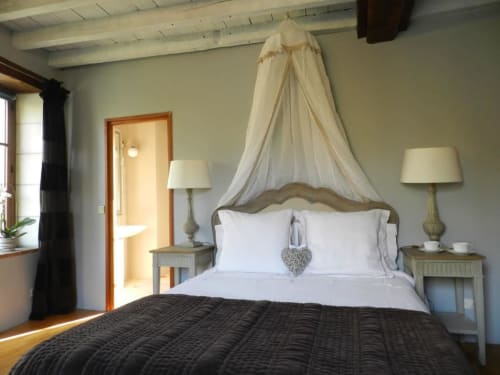 Élégante chambre double au Moulin De La Chevrière avec lit à baldaquin, draps blancs et vue sur la rivière à Saché