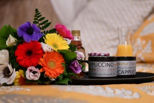 Fleurs de gerbera colorées avec tasse de cappuccino et jus d'orange sur table aux gîtes des châteaux