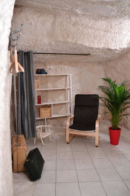 Intérieur rustique du gîte aux châteaux avec chaise en bois, étagères, plante et valises vintage