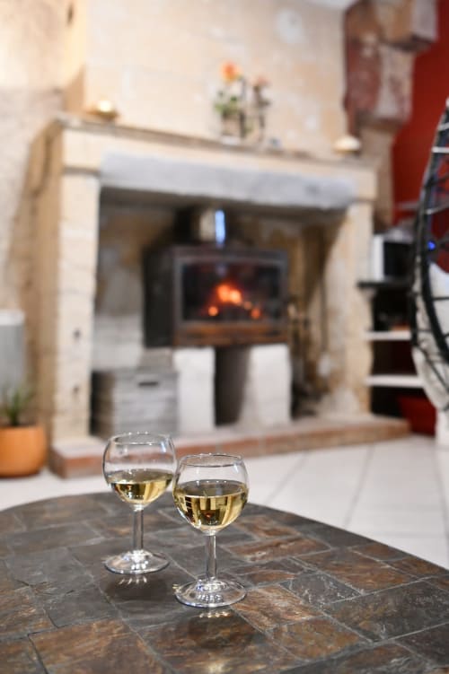 Deux verres de vin blanc sur une table en ardoise devant la cheminée aux gîtes des châteaux