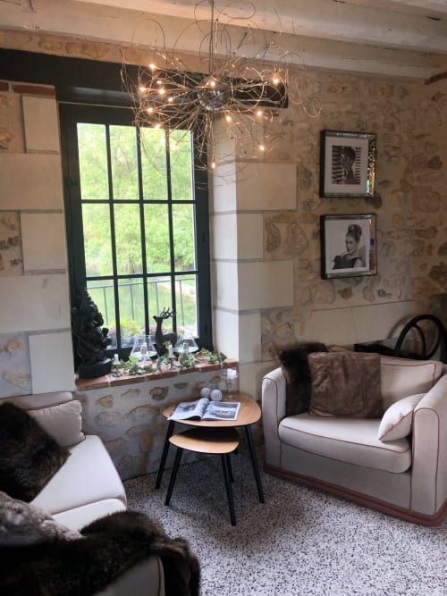 Élégante chambre double au Moulin De La Chevrière avec fauteuils crème, vue sur la rivière et luminaire suspendu design en métal
