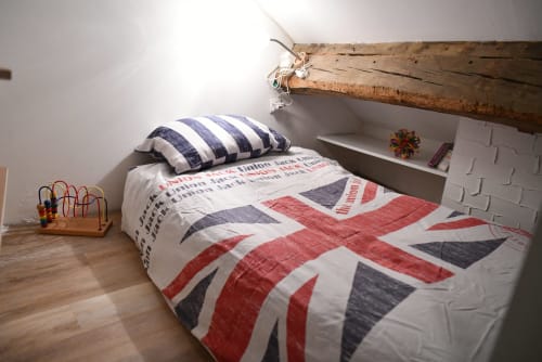 Chambre accueillante aux Gîtes des Châteaux avec literie Union Jack, oreiller rayé, poutres apparentes et vue sur la rivière