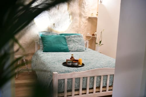 Chambre cosy aux Gîtes des Châteaux avec literie à motifs, coussins turquoise et lumière naturelle à Vallières-les-Grandes