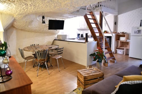 Spacieux gîte troglodytique aux Gîtes des châteaux avec salle à manger, cuisine, escalier en bois et équipements modernes