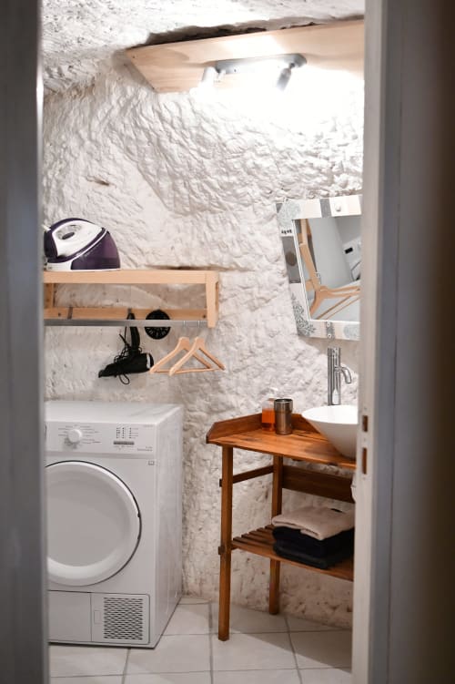 Buanderie troglodytique aux Gîtes des Châteaux à Vallières-les-Grandes : sèche-linge, table en bois et décor blanc