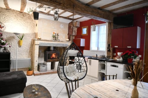 Cuisine rustique aux murs rouges, foyer, chaise suspendue et salle à manger aux gîtes des châteaux
