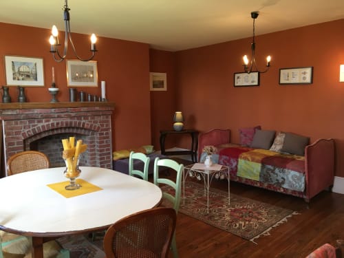 Warm orange-walled living area at La Chatellenie BnB with fireplace, dining table, and comfortable seating in Saint Aubin le