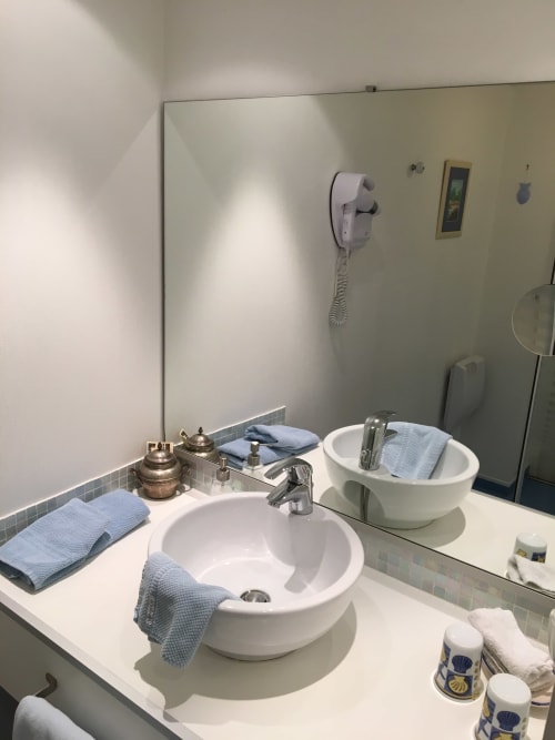 Dual round white vessel sinks with blue towels in Superior Room bathroom at La Chatellenie, Saint Aubin le Cauf