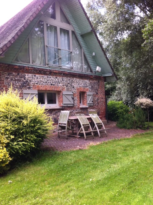 Brick cottage exterior with peaked roof, lounge chairs on patio, lush garden at La Chatellenie B&B in Saint-Aubin-le-Cauf
