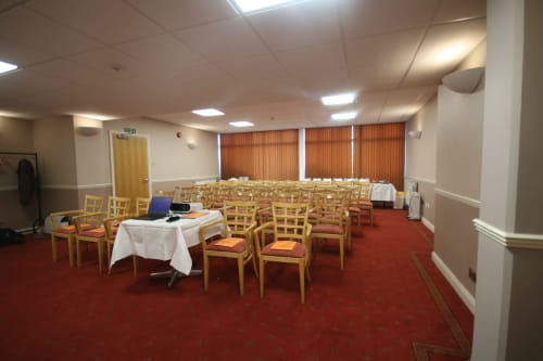 Salle de conférence de l'hôtel La Trelade avec chaises en bois, moquette rouge et stores orange à Saint-Martin