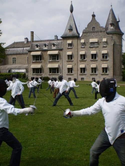 Événement de groupe au Château d'Hassonville à Marche-en-Famenne avec des participants en chemises blanches sur la pelouse verte