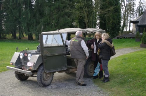 Guide with two guests at Château d'Hassonville's vintage military vehicle in Marche-en-Famenne, Belgium