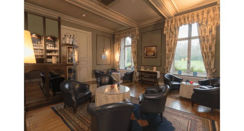 Elegantes Wohnzimmer des Château d'Hassonville B&B in Marche-en-Famenne mit Ledersesseln, Kamin und Landschaftsblick