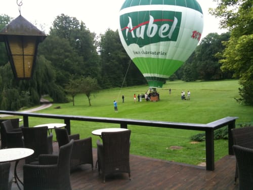 Château d'Hassonville hot air balloon landing on grounds in Marche-en-Famenne, Belgium with terrace seating