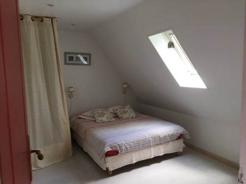Bright attic bedroom at La Chatellerie cottage with skylight, striped bedding, and countryside view in Saint Aubin le Cauf