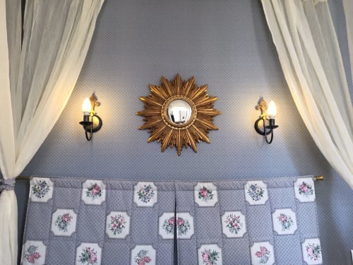 Elegant Superior Room at La Chatellenie B&B with gold sunburst mirror, floral wall sconces, and patterned curtains