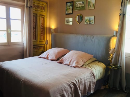 Cozy bedroom at Saint Martin B&B in Ollioules with gray upholstered bed, pink pillows, and warm lighting