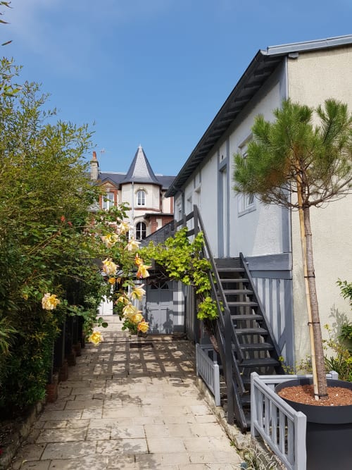 La cour de l'hôtel Les Cabines à Houlgate avec allée pavée, roses jaunes et architecture victorienne sous un ciel dégagé