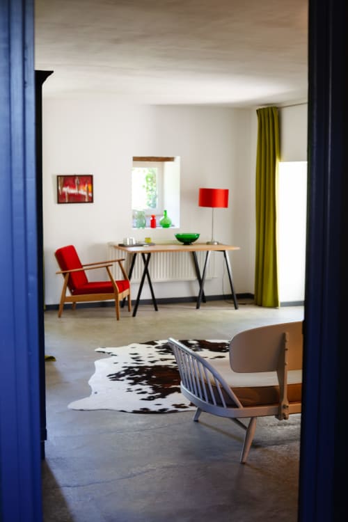 Modern zitgedeelte in de Saint André kamer van Hotel Moulin Renaudiots, Autun, met rode fauteuil, bureau en eigentijds meubilair