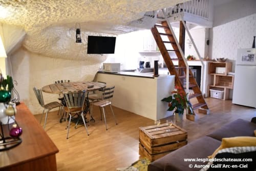 Intérieur du gîte des châteaux avec salle à manger, cuisine, escalier en bois et salon à Vallières-les-Grandes