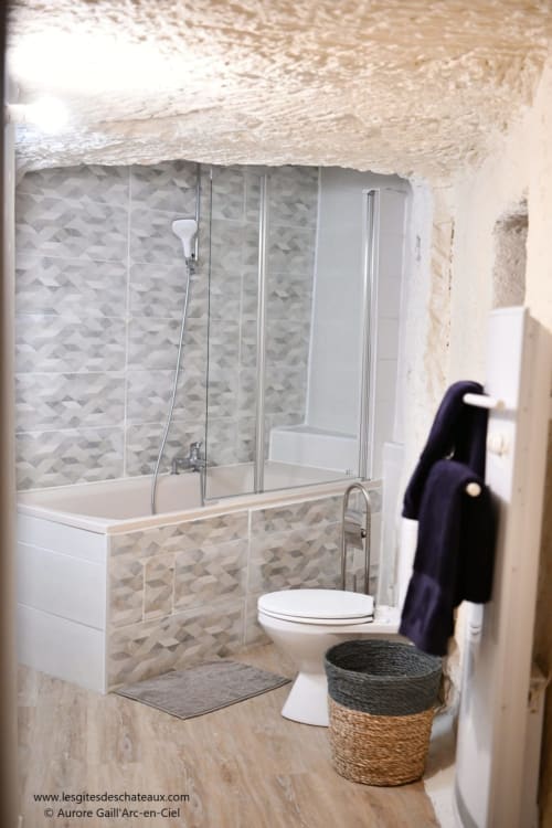 Salle de bains moderne avec douche en pierre, baignoire et toilettes au gîte Les Châteaux à Vallières-les-Grandes