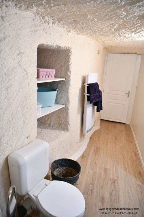 Salle de bain du gîte Le troglo'riel aux gîtes des châteaux, avec toilettes, rangements intégrés et porte-serviettes