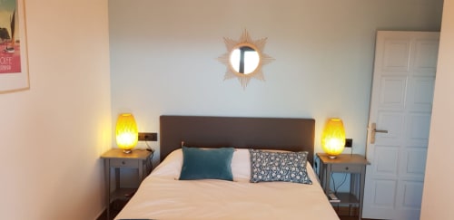 Ty Pals B&B bedroom in Pals with queen bed, dark headboard, teal pillows, brass sun mirror, and yellow lamps
