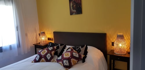Cozy bedroom at Ty Pals B&B in Pals with yellow walls, dark headboard, patterned pillows, and ambient lighting