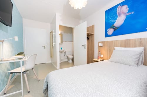 Chambre moderne avec lit blanc, bureau de travail et salle de bain privée à la maison d'hôtes Un Air De Famille à Vittel