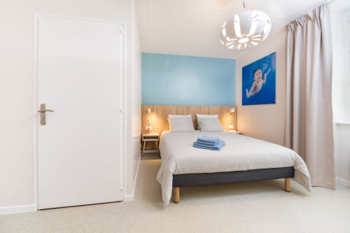 Chambre double moderne à Un Air De Famille à Vittel avec mur d'accent bleu, tête de lit en bois et éclairage contemporain
