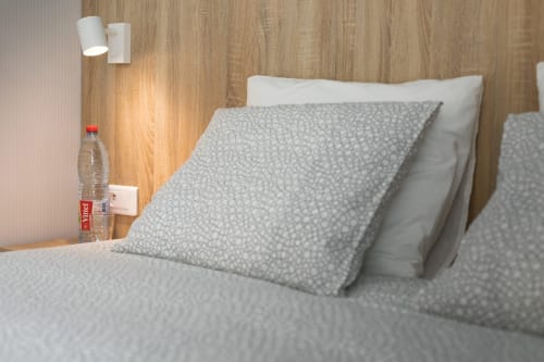 Chambre double moderne à Un Air De Famille B&B à Vittel avec coussins à motifs, tête de lit blanche, murs en bois et table de nuit