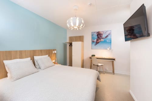 Chambre double moderne à Un Air De Famille à Vittel avec mur d'accent bleu ciel, lit en bois, TV écran plat et bureau de travail