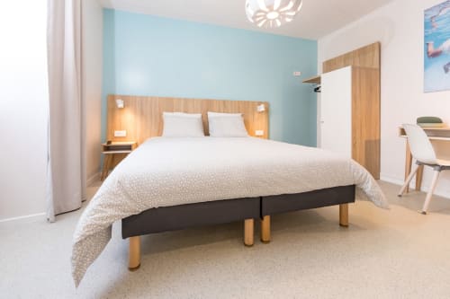 Chambre double moderne à Un Air De Famille, Vittel avec mur d'accent turquoise, tête de lit en bois et vue sur jardin