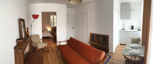 L'appartement L'OTIS à Dinan dispose d'un séjour avec canapé rouille, mobilier en bois et vue ouverte sur la cuisine