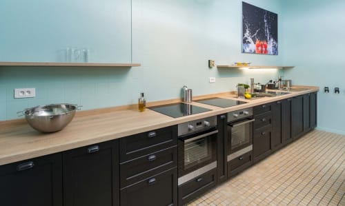 Cuisine moderne aux murs bleu clair, armoires noires, plans de travail en bois à Un Air De Famille B&B à Vittel, France
