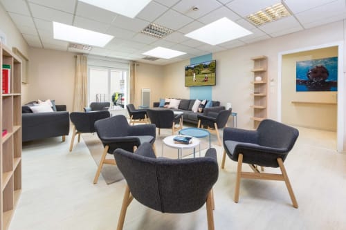 Espace commun contemporain du gîte Un Air De Famille à Vittel avec chaises en charbon, étagères bois et décoration actuelle