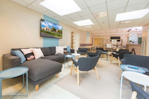 Salon moderne de l'Un Air De Famille BnB à Vittel avec canapé gris, fauteuils bleus et téléviseur écran plat