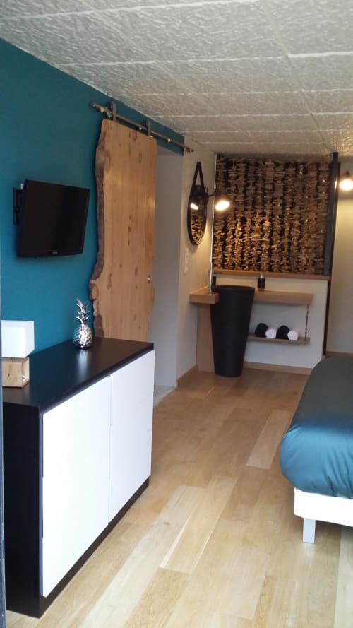 Camera da letto in cottage moderno con parete accent turchese, TV a schermo piatto, porta a sbarramento in legno e biancheria blu presso La Maison D'ambrine