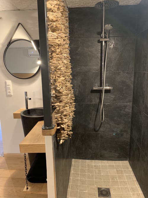 Bagno moderno nella gite di Dylan a Chamaret con doccia in piastrelle nere, mobile lavabo in legno e parete in pietra naturale
