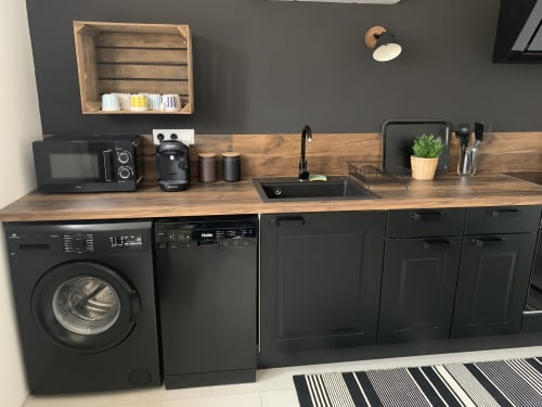 Moderne keuken in Leny's cottage bij La Maison D'ambrine, Chamaret, met zwarte apparaten en houten werkblad