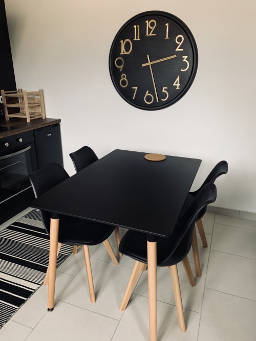 Moderne zwarte eettafel met houten stoelen in de cottage-keuken van Leny bij La Maison D'ambrine, Chamaret, met wandklok