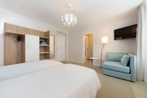 Suite petite et moderne à Un Air De Famille à Vittel avec lit queen-size, canapé bleu, télévision écran plat et mobilier en bois