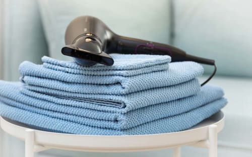 Pile de serviettes bleues avec un sèche-cheveux à la boutique hôtel Un Air De Famille à Vittel