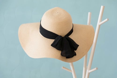 Chapeau de paille à larges bords avec nœud noir sur fond bleu clair à Un Air De Famille, Vittel