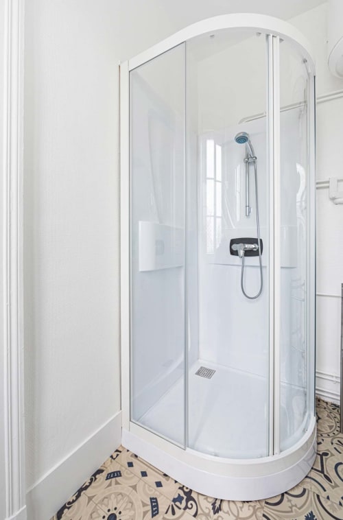 Cabine de douche en verre courbé moderne dans la salle de bains lumineuse de l'hôtel-boutique Un Air De Famille, Vittel
