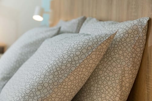 Coussins de décoration aux motifs géométriques circulaires sur le lit de la maison d'hôtes Un Air De Famille à Vittel, France