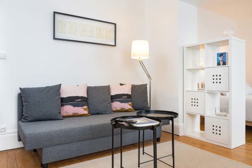Studio à Un Air De Famille à Vittel avec canapé gris, tables noires, lampadaire et rangements blancs