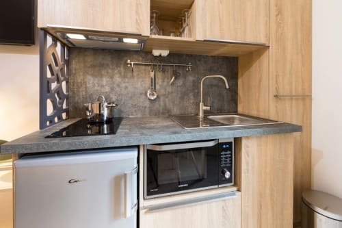Petite kitchenette moderne avec évier, plaque de cuisson, micro-ondes et réfrigérateur dans l'appartement Studio Vittel