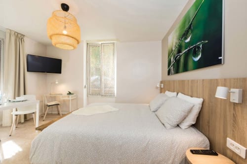 Studio moderne à Un Air De Famille B&B à Vittel avec lit, TV, tête de lit en bois et luminaire suspendu en rotin