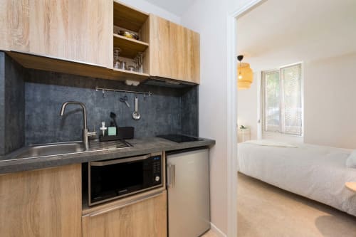 Kitchenette moderne avec crédence noire, meubles en bois et électroménagers en acier inoxydable à Un Air De Famille, Vittel